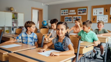 Kinder im Klassenzimmer sitzen an ihren Schreibtischen.