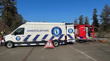 Notfallfahrzeuge auf einem Parkplatz bei Tageslicht.",