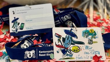 Basler Fastnachtsplakette mit Kordel auf Konfetti verteilt.