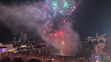 Feuerwerk über einer belebten Brücke in einer Stadt bei Nacht.