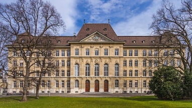 Historisches Gebäude mit zwei Bäumen im Vordergrund.",