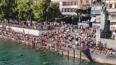 Menschenmenge entspannt und schwimmt am Flussufer bei sonnigem Wetter.