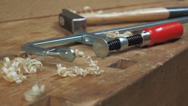Werkbank mit Schraubzwinge und Hobelspänen.