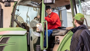 Landwirt im Traktor spricht mit Mechaniker.