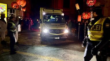 Die Sanität Basel fährt in Begleitung der Kantonspolizei Basel-Stadt durch eine Menschenmenge beim Morgestraich.