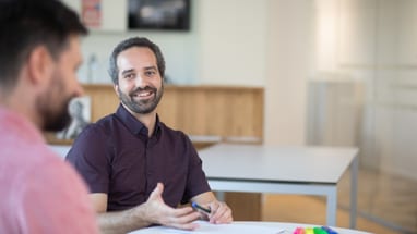 Zwei Männer im Gespräch an einem Tisch im Büro.