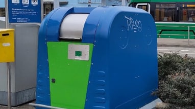 Blaue und grüne Recyclingstation auf einem öffentlichen Platz.