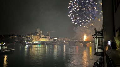 Feuerwerk über der Stadt bei Nacht mit Fluss im Vordergrund.