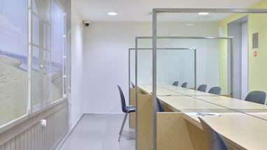 Leerer Besprechungsraum mit langen Tischen und Trennwänden.