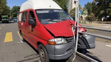 Roter Lieferwagen mit beschädigter Front auf der Strasse.