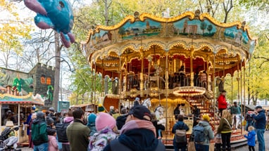 Menschen vor einem beleuchteten Karussell im Park mit Ballon.