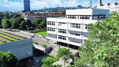 Moderne Stadtlandschaft mit Bürogebäude und Bäumen im Vordergrund.