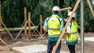 Zwei Bauarbeiter in gelben Westen auf einer Baustelle.