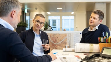 Unterhaltung von drei Personen am Schreibtisch