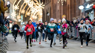Kinderlauf auf beleuchteter Stadtstrasse bei Nacht.