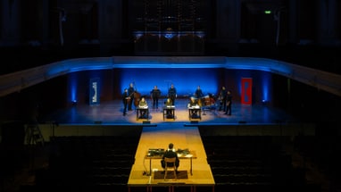 Orchesterprobe auf beleuchteter Bühne in einem Konzertsaal.