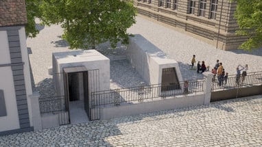 Gedenkstätte mit Baum und Besuchergruppe neben historischem Gebäude.