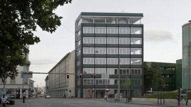 Strassenszene mit modernem Gebäude und Bäumen bei einer Kreuzung.