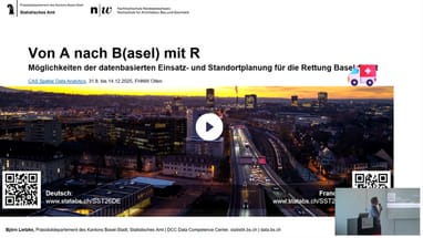 Präsentationsfolie mit Stadtbild des nächtlichen Basel und einem Ambulanzfahrzeug.