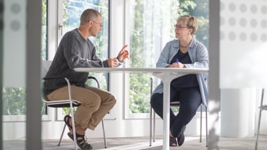 Zwei Personen sitzen an einem Tisch und unterhalten sich.