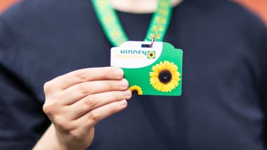 Person hält Sonnenblumenpass auf grünem Band.