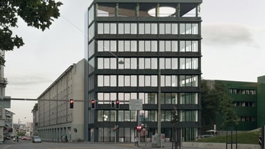 Moderne Glasfassadengebäude an einer Strasse bei Dämmerung.