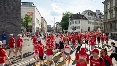 Menschenmenge in roter Kleidung bei einer Strassenparade in der Stadt.