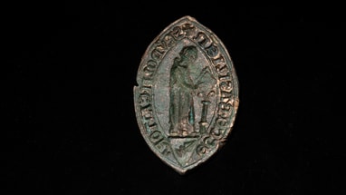 Mittelalterliches Siegel mit Figur und Inschrift auf schwarzem Hintergrund.