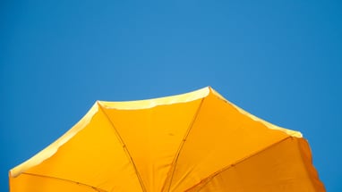 Gelber Sonnenschirm vor blauem Himmel.