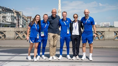 Gruppe von Menschen in Sportkleidung auf Brücke bei Sonnenschein.