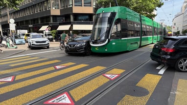 Grüne Strassenbahn kollidiert mit Auto auf städtischer Kreuzung.