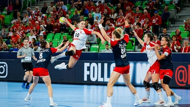 Handballspiel mit Spielerinnen in Aktion.