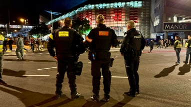 Polizisten auf der Strasse bei Nacht vor Gebäude mit rotem Licht.