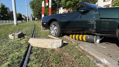 Auto auf Gehweg neben Strassenbahngleisen nach Unfall.