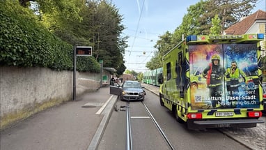 Auto blockiert Strassenbahngeleise neben Rettungsfahrzeug.