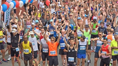 Menschenmenge beim Marathonstart, bunte Luftballons über ihnen.