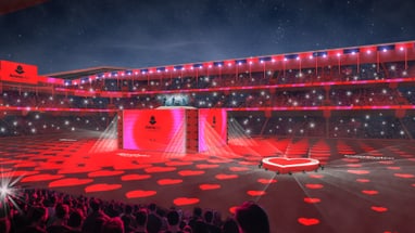 Rot erleuchtete Arena mit Herzprojektionen und Bühne.",