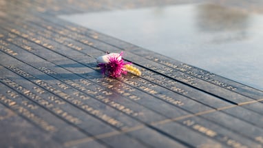 Blume auf Gedenktafel mit eingravierten Namen.