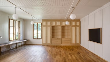 Leerer Raum mit Holzboden und Schränken.