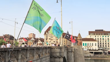 Brücke in Basel mit wehenden bunten Fahnen im Wind.