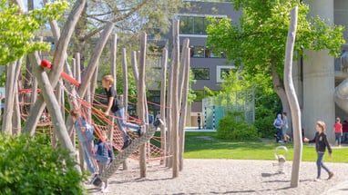 Kinder klettern auf einem Spielplatz mit Holzstrukturen.