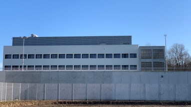 Modernes Gebäude mit mehreren Fenstern hinter einem Zaun.