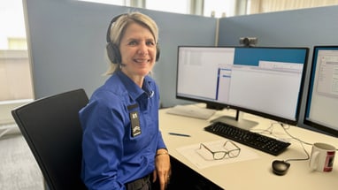 Frau mit Headset sitzt an Schreibtisch mit zwei Monitoren.