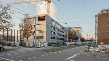 Gebäude im Bau mit Baukran an städtischer Strasse.