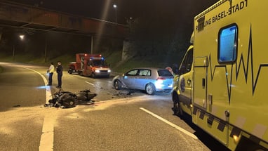 Unfallstelle bei Nacht mit Krankenwagen, Auto und Motorradtrümmern.",  