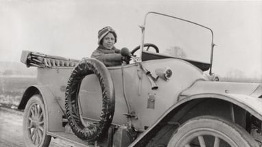 Person in einem alten Auto auf einer Landstrasse.