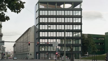 Moderne Glasfassadengebäude an einer Strasse bei Dämmerung.