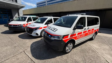 Drei Polizeiautos parken nebeneinander auf einem Parkplatz.