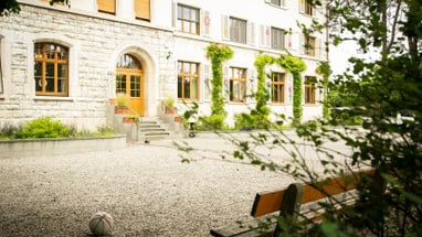 Bank und Ball vor einem alten Stein- und Holzgebäude.