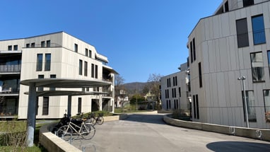 Moderne Wohngebäude mit Fahrradständer auf einem sonnigen Platz.